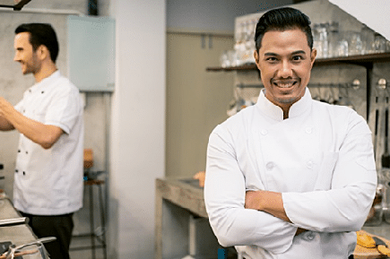 Smiling man wearing a white clean chef uniform