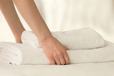 Close up of a hand holding a stack of fresh, clean towels.